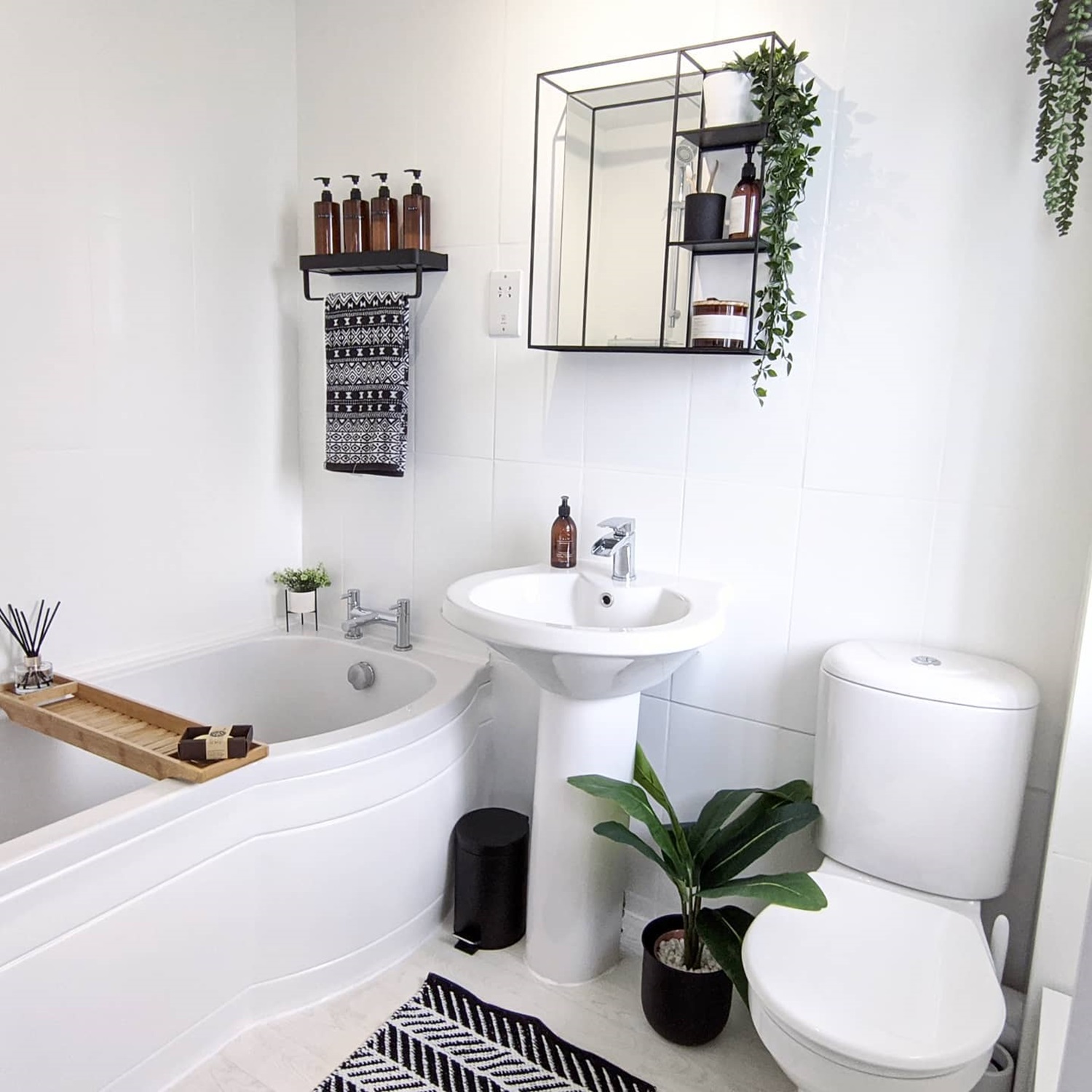 Modern bathroom featuring plants, a bathtub, round toilet, and black and white decor