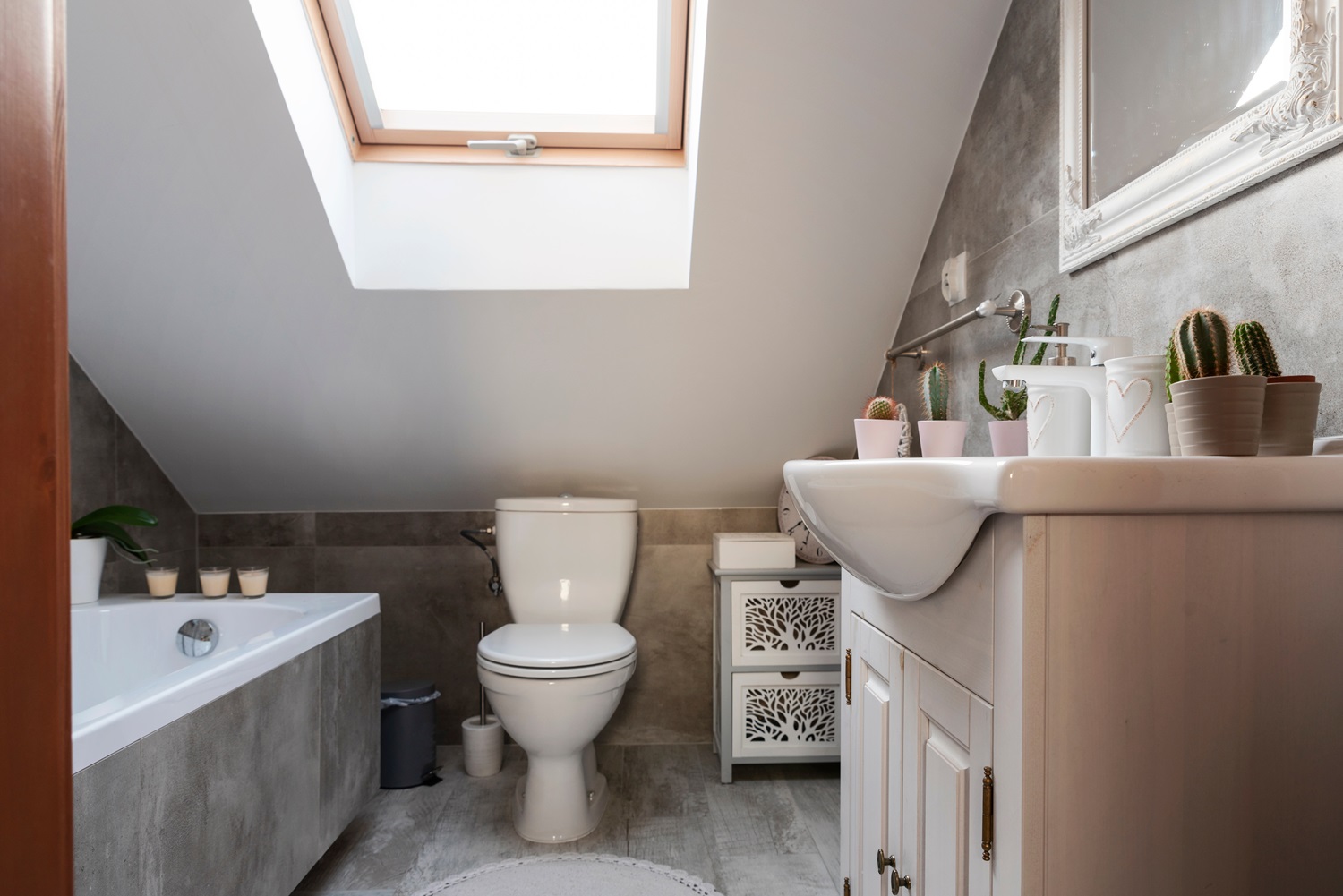 Modern bathroom features a skylight, bathtub, toilet, sink, and decorative plants