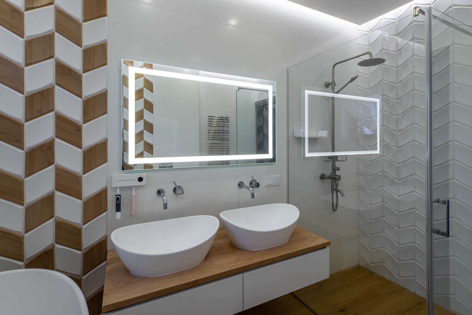 Modern bathroom featuring double sinks, large mirrors, and a glass-enclosed shower