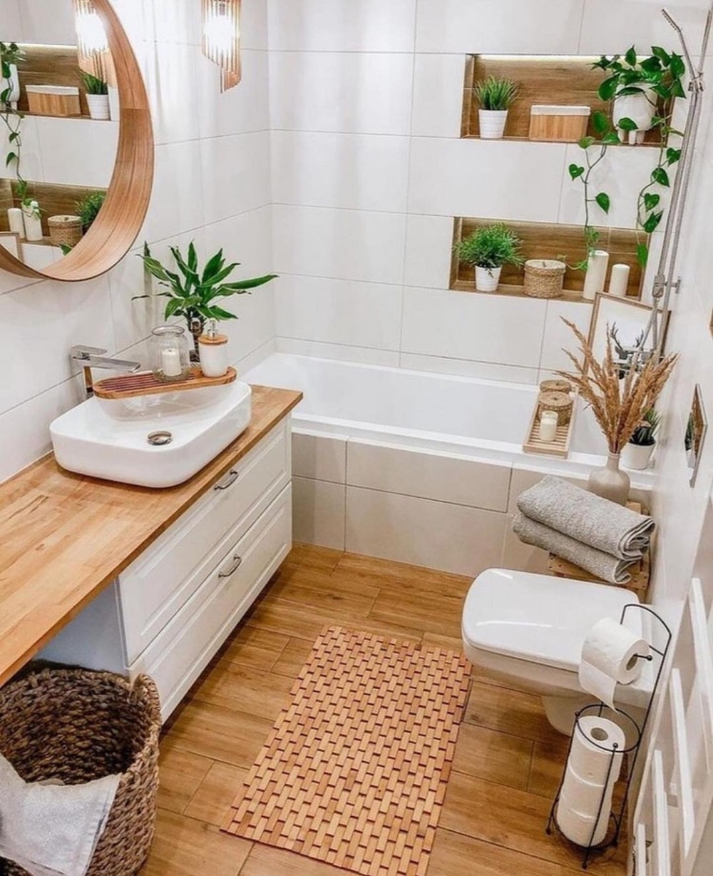 A modern bathroom with plants, a round mirror, a bathtub, and wooden accents