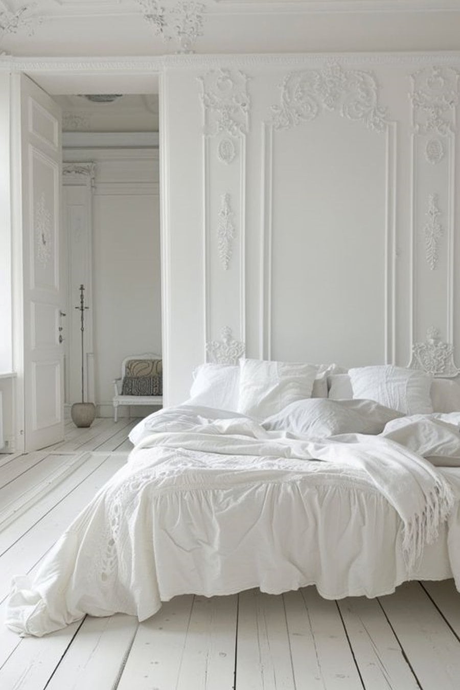 Elegant bedroom with ornate wall details, white bedding, and a minimalist, vintage-inspired design.