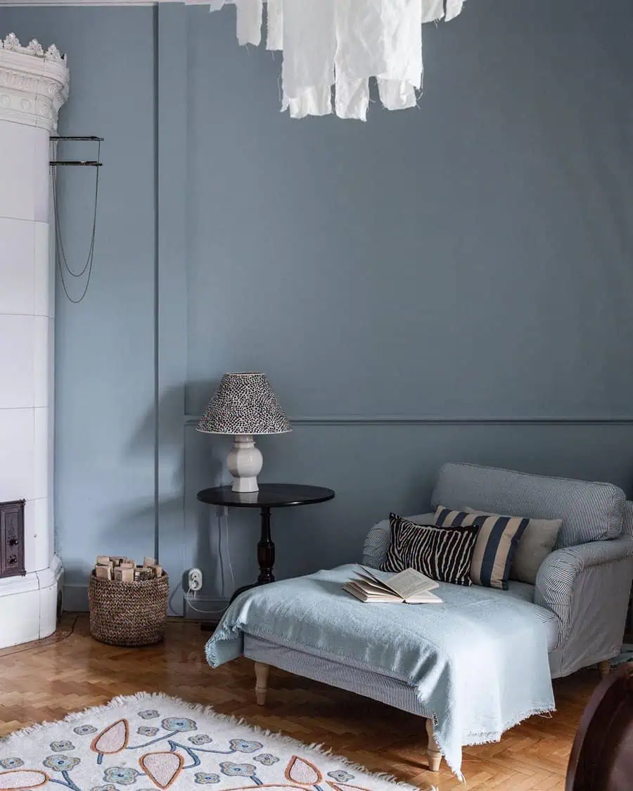 Cozy room with armchair, side table, lamp, and fireplace; light blue and neutral tones