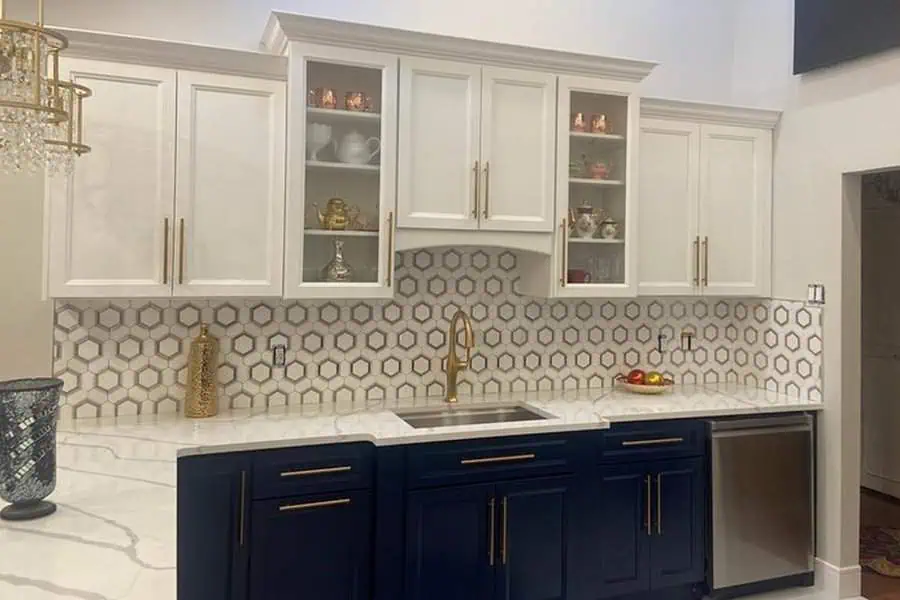 Modern kitchen with white cabinets, hexagonal backsplash, and dark blue lower cabinets