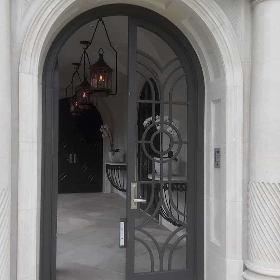 Elegant arched door with decorative wrought iron design leading to a sophisticated entryway with hanging lanterns