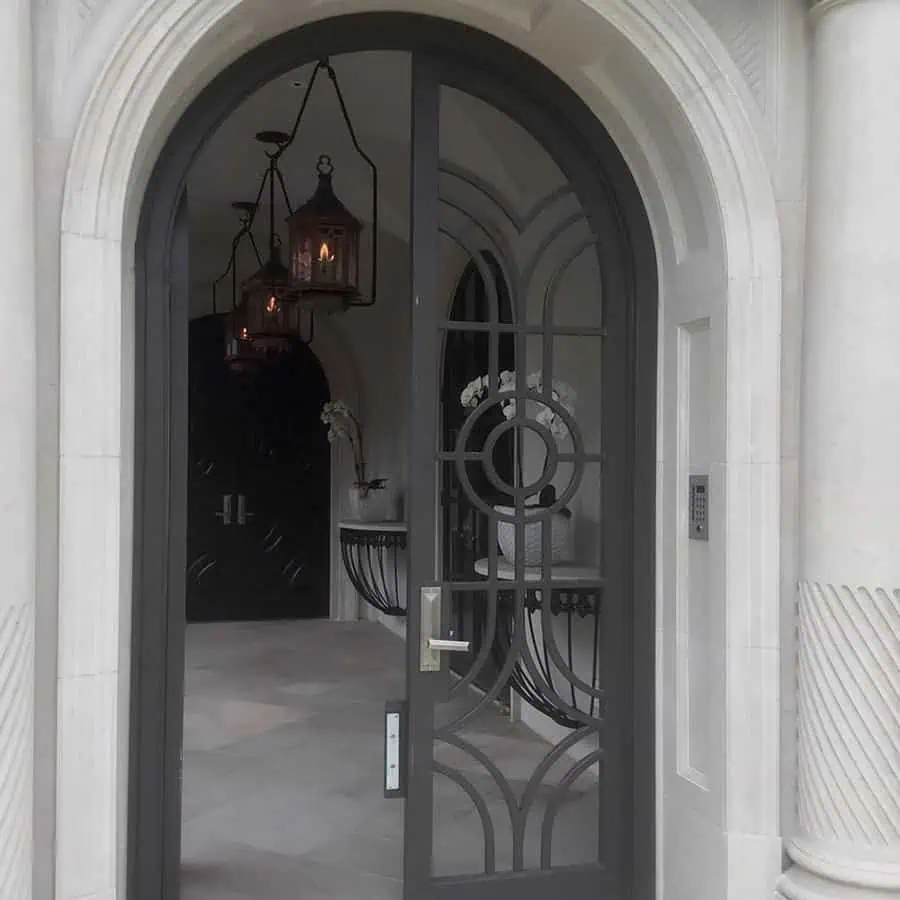 Elegant arched door with decorative wrought iron design leading to a sophisticated entryway with hanging lanterns