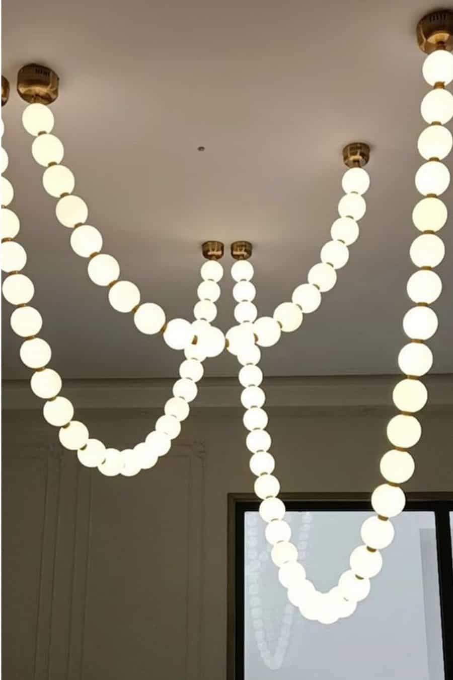 Modern chandelier with round bulbs arranged in draped, necklace-like strands hanging from a ceiling