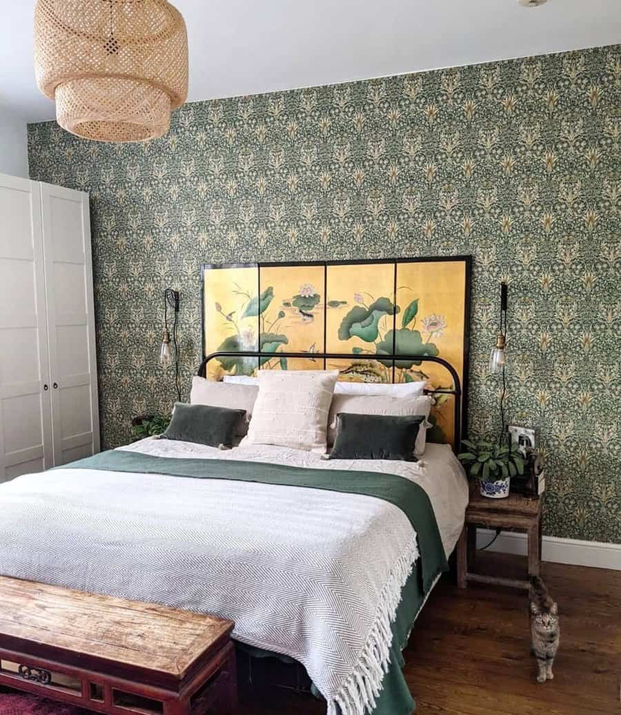 Bedroom featuring floral wallpaper, a bed with green and white bedding, a bench, and nightstands with lamps and plants