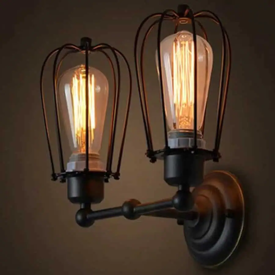 Industrial-style wall sconce with two exposed Edison bulbs in wire cages against a dark backdrop