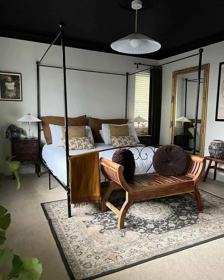 Bedroom with a canopy bed, bench at the foot of the bed, large mirror, and a rug on the floor