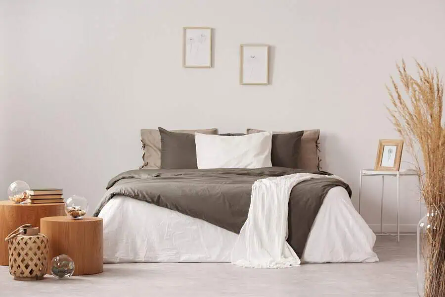 Modern bedroom with neutral tones, layered bedding, wooden side tables, and minimalist wall art.