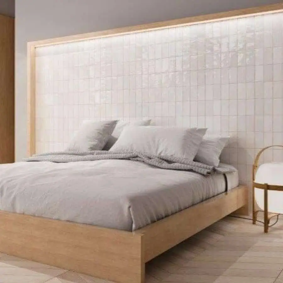 Minimalist bedroom with wooden bed frame, white pillows, and a tiled illuminated headboard.