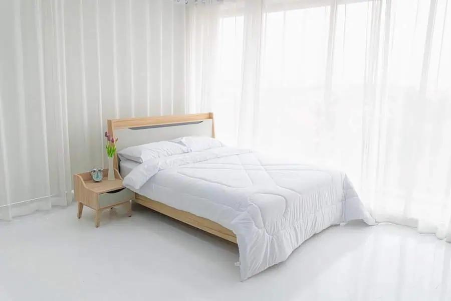 A minimalist bedroom with a wooden bed frame and white bedding.