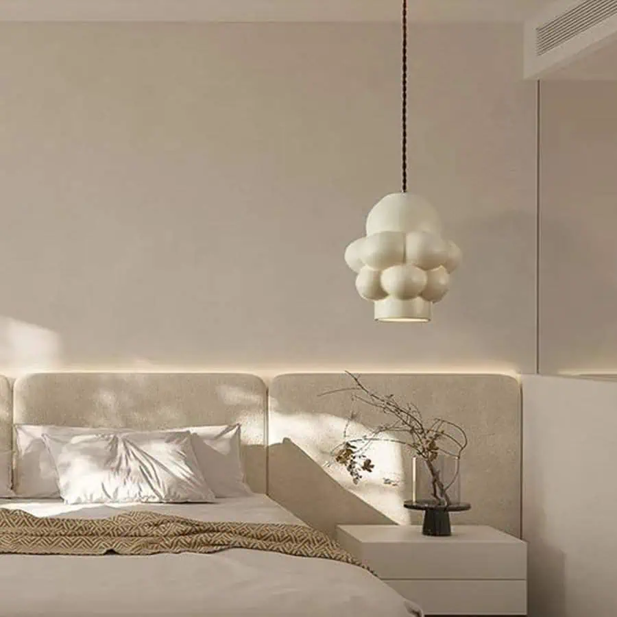 Modern bedroom with a plush headboard, unique cloud-like pendant light, and minimalist decor.