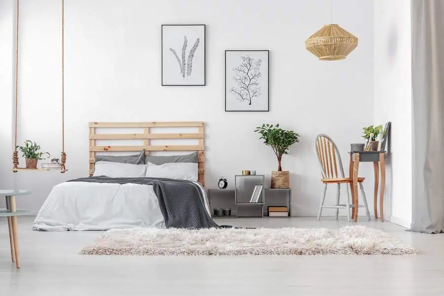 Scandinavian-style bedroom with a wooden bed frame, minimalist decor, a cozy rug, and a small workspace.