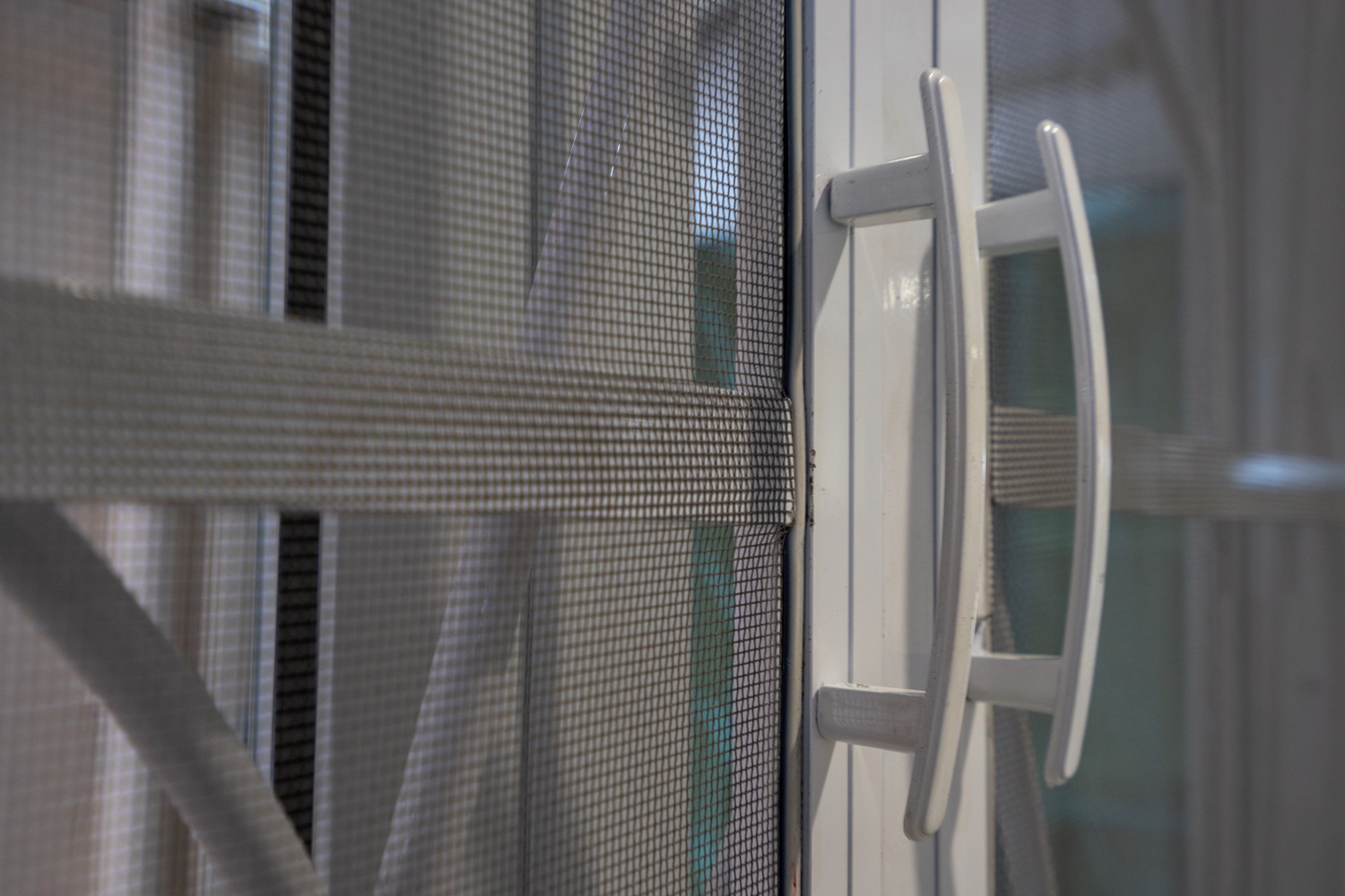 Close-up of a window with a mesh screen and white handle