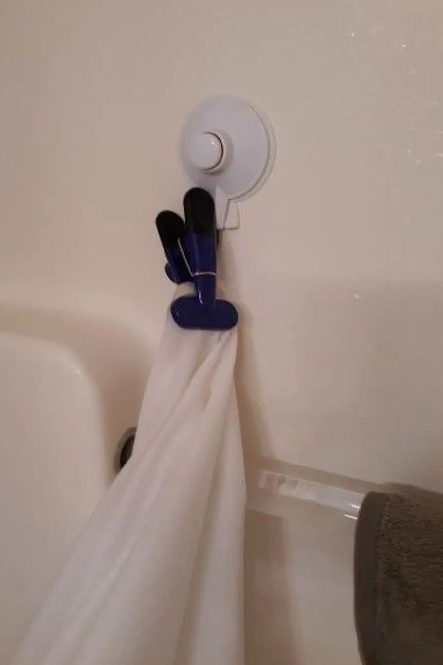 White shower curtain secured with a blue and black clip