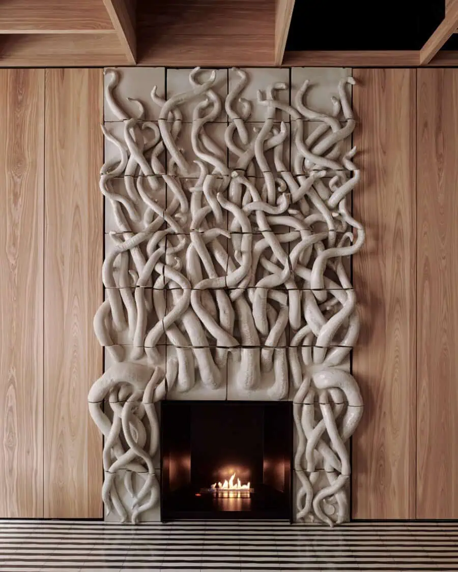 Artistic fireplace design featuring a textured wall sculpture, modern firebox, and sleek wooden accents.