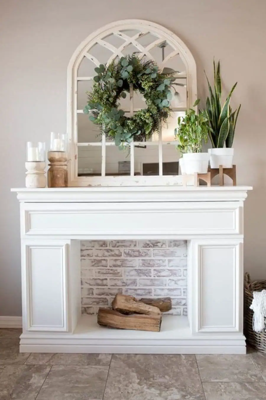 Charming fireplace with a white mantel, decorative mirror, greenery, and rustic wood accents.