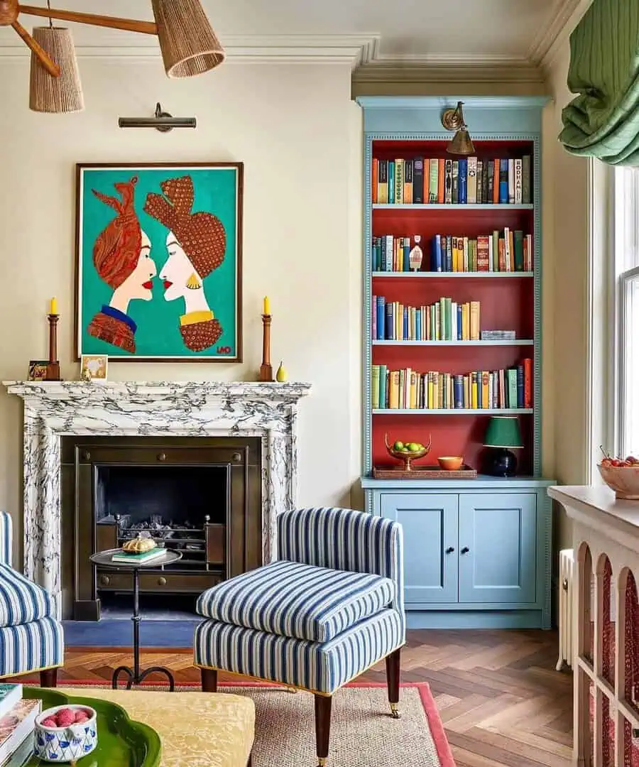 Vibrant living room with a marble fireplace, colorful artwork above, and stylish bookshelves.