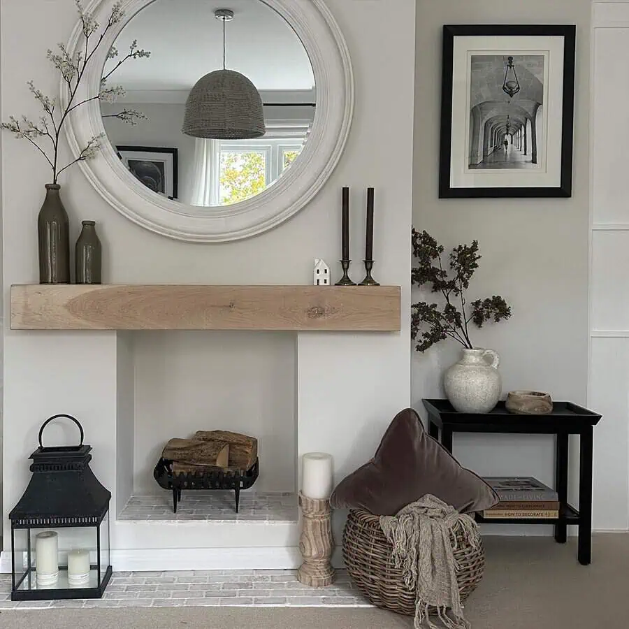 Minimalist fireplace with a wooden mantel, round mirror, and stylish decorative accents.