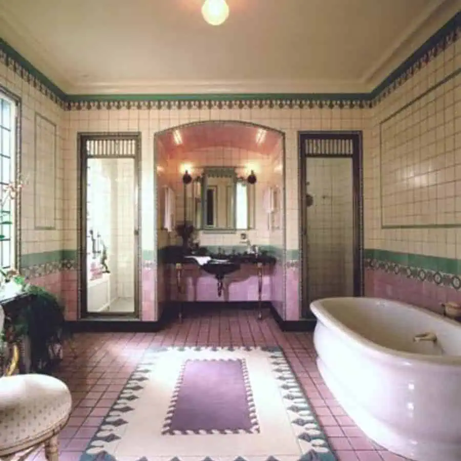 Vintage Art Deco bathroom with pastel tiles, freestanding bathtub, and decorative rug.