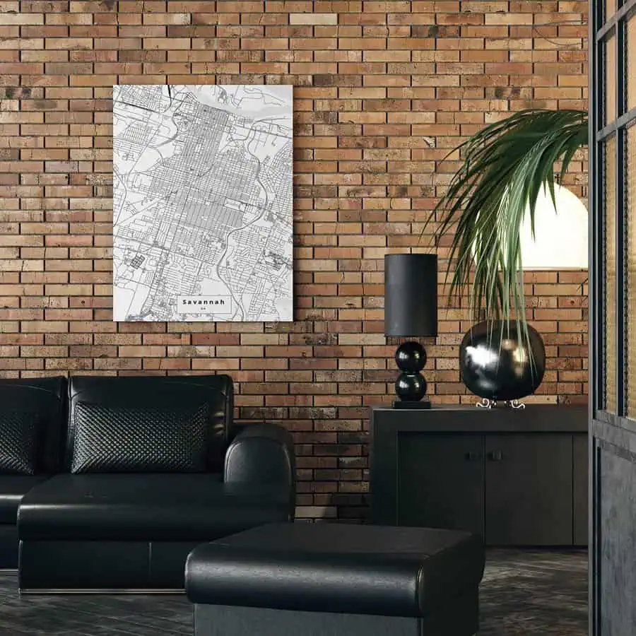 Minimalist living room with a black leather sofa, brick accent wall, and framed city map.