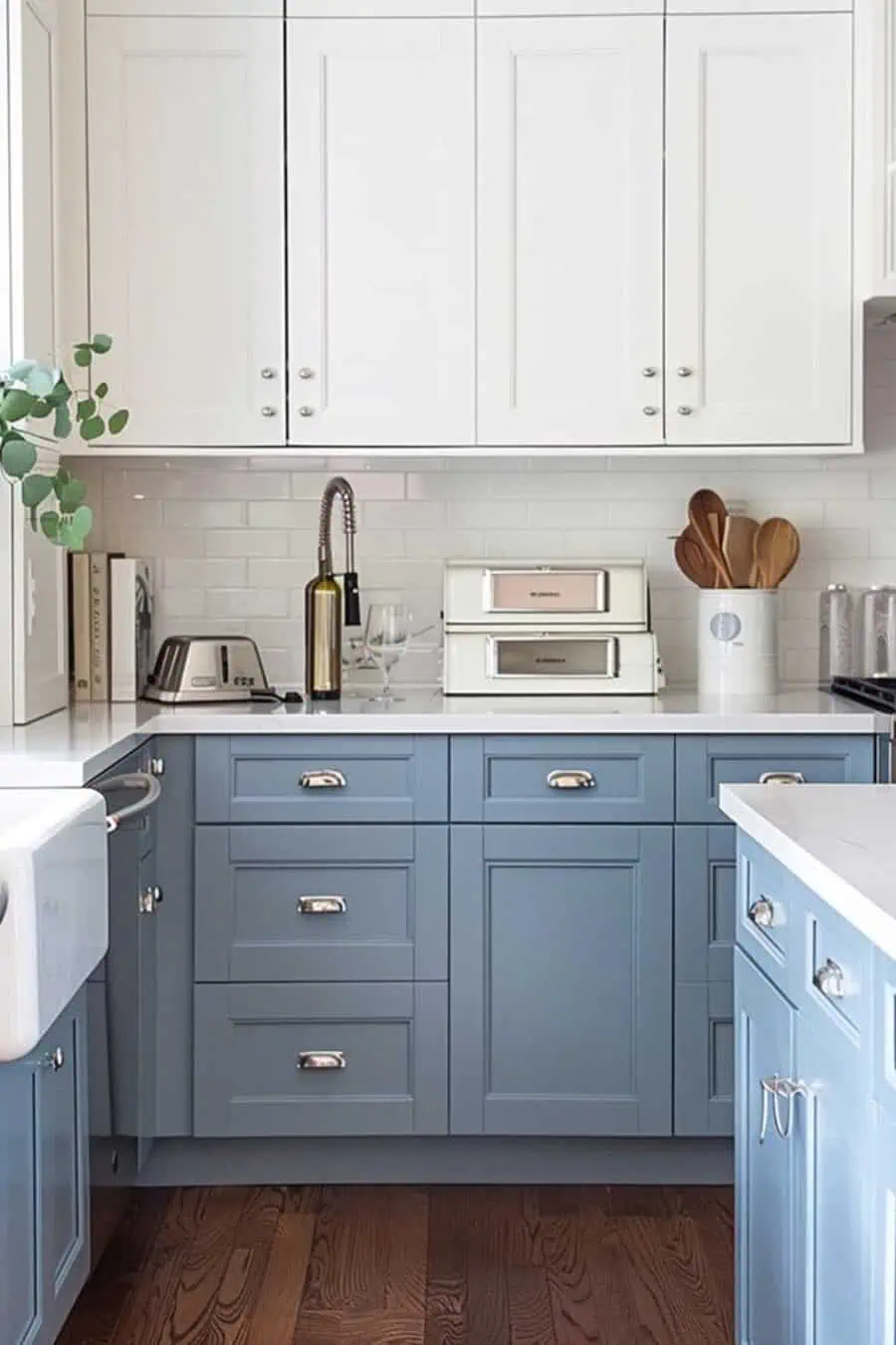 A small kitchen with light blue lower cabinets, white upper cabinets, and a subway tile backsplash.