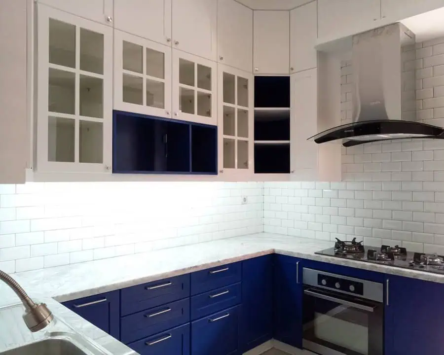 Modern kitchen with blue cabinets, white countertops, and glass-panel upper cabinets