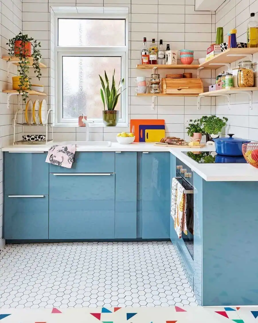 A vibrant kitchen with glossy blue cabinets, open wooden shelving, and a white hexagon tile floor.