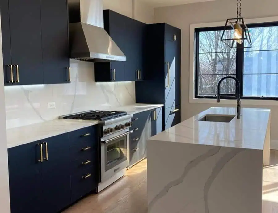 A sleek kitchen with dark cabinetry, marble countertops, and a stainless steel hood over the stove.