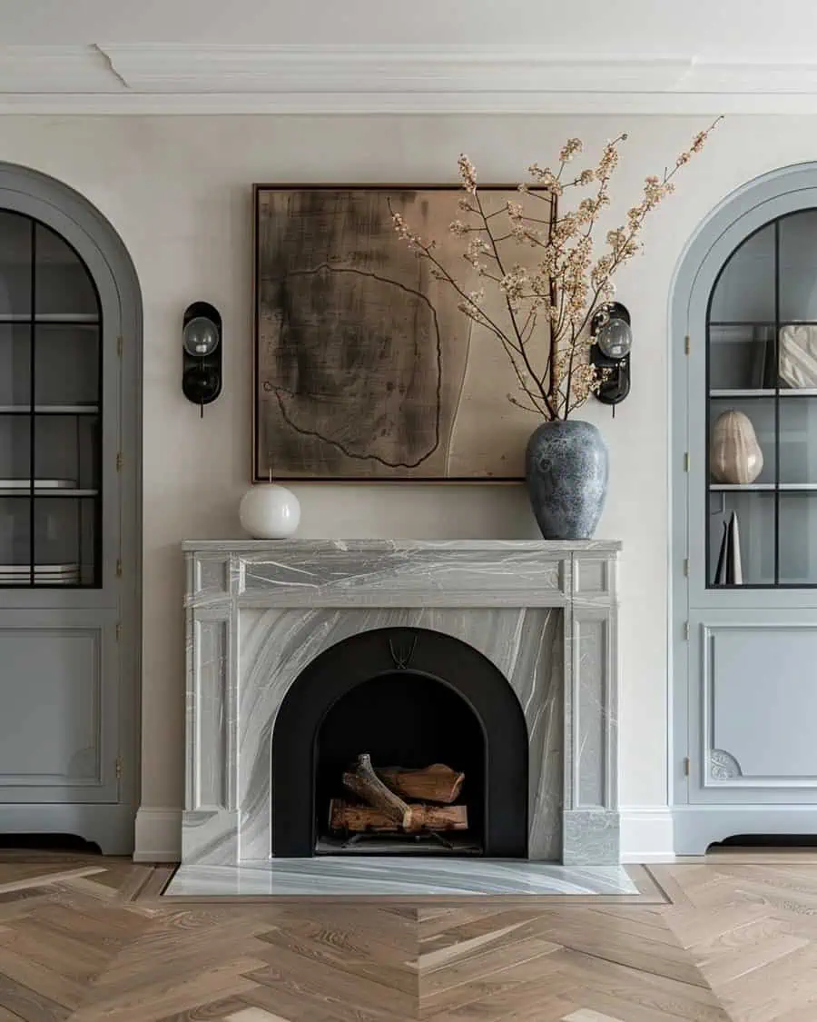 Chic fireplace decor featuring a marble mantel, modern artwork, and a decorative vase with branches.