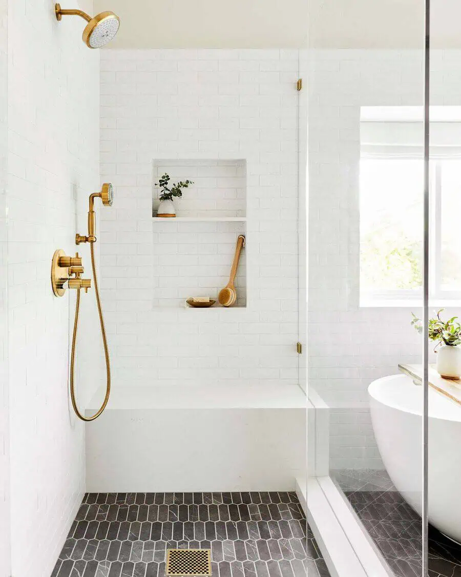 Shower with classic design, gold fixtures, white subway tiles, and black hexagon tile floor.