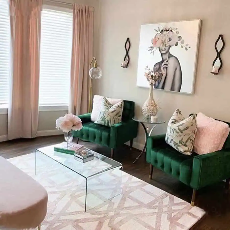 Modern living room with emerald green chairs, glass coffee table, and floral wall art.