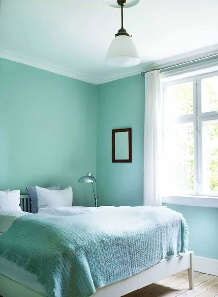 Light-filled bedroom with mint green walls, white bedding, and soft natural textures.