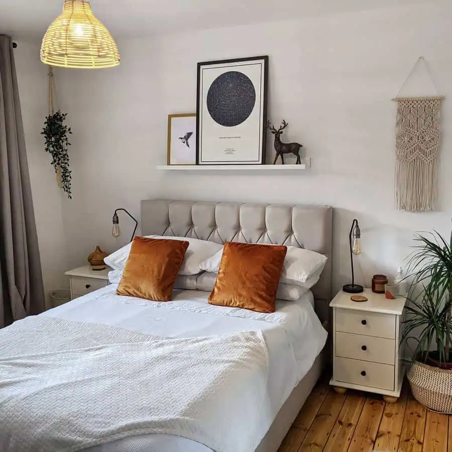 Cozy bedroom featuring a tufted headboard, rust-colored pillows, and bohemian wall decor.