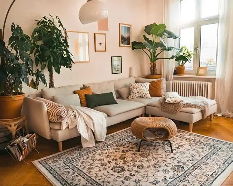 Warm living room with an L-shaped sofa, indoor plants, and a patterned rug.