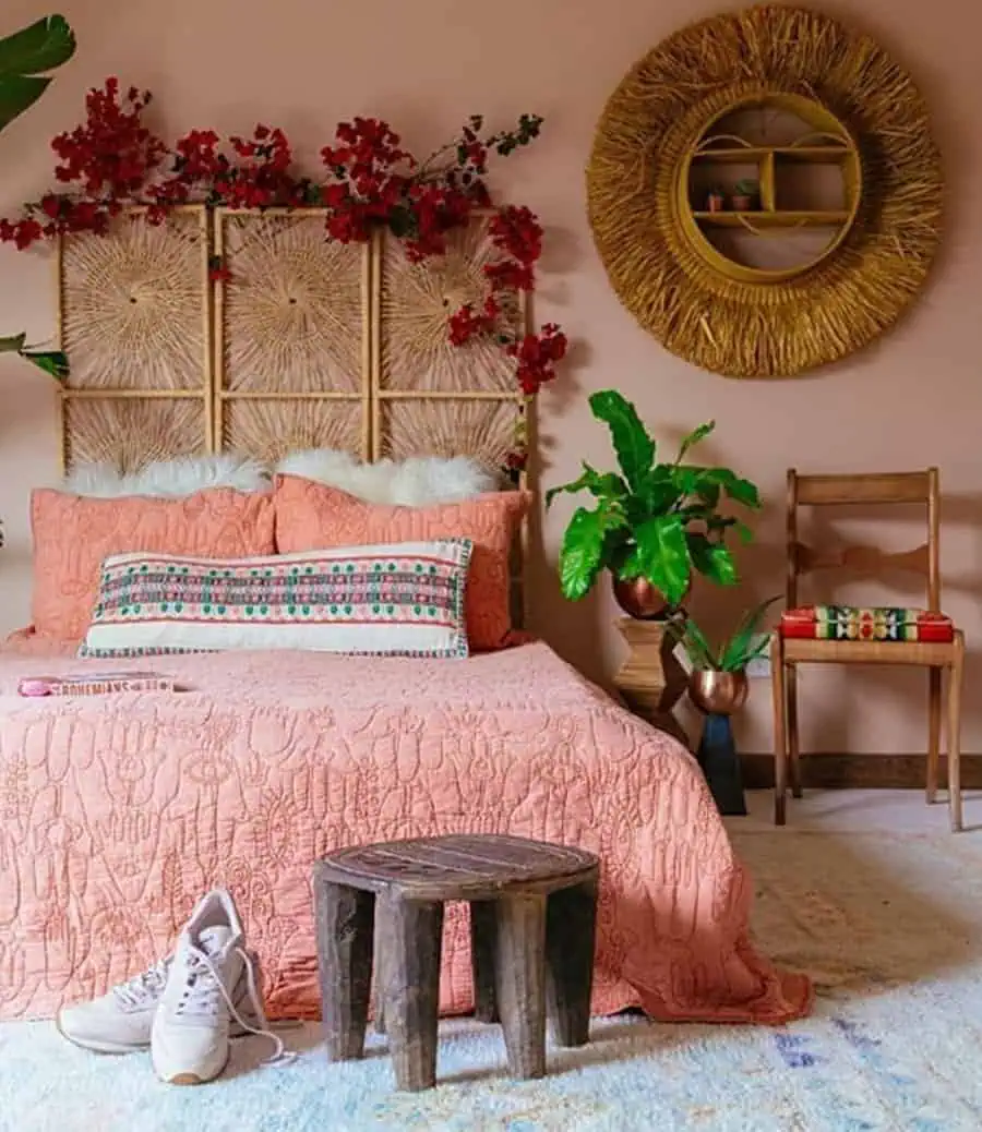 Bohemian bedroom with coral bedding, rattan headboard, and vibrant plant decor.