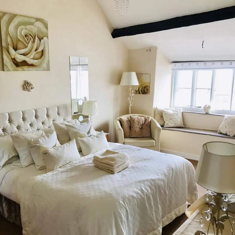 Elegant bedroom with tufted headboard, soft neutral tones, and a cozy window seat.