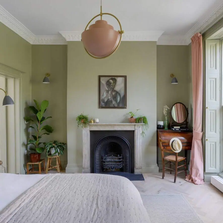 Charming bedroom with sage green walls, a vintage fireplace, and a classic vanity set.