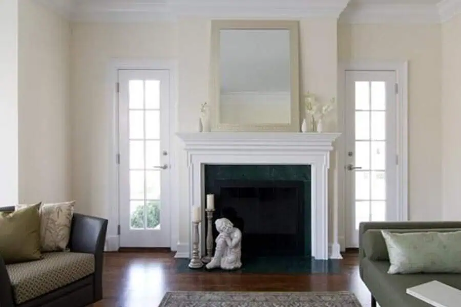 Classic living room with a white fireplace, French doors, and soft green accents.