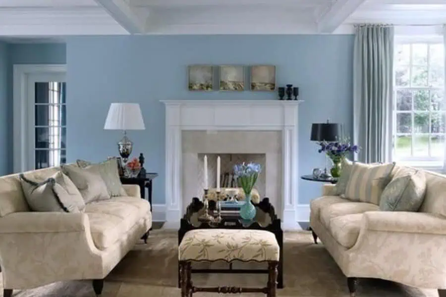 The soft blue walls paired with neutral furniture give this living room a calm and airy feel, making it appear more spacious.