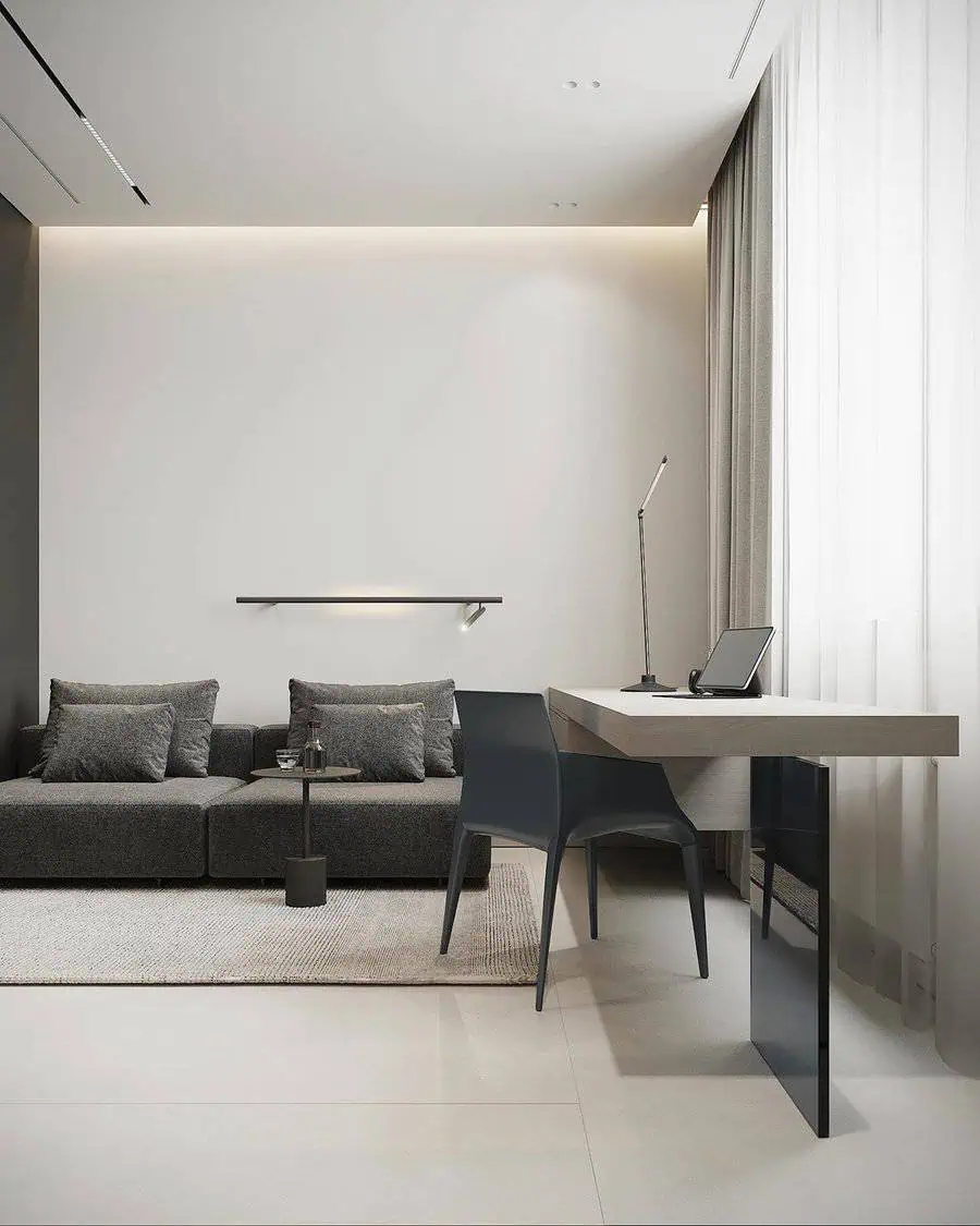 Modern living space with a sleek gray sofa, minimalist desk, and soft natural lighting.