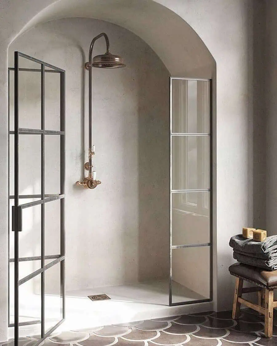 Contemporary shower with arched ceiling, glass doors, and brass fixtures in neutral tones.