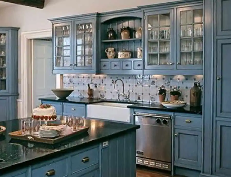 A traditional kitchen with blue cabinetry, glass-front upper cabinets, and a farmhouse sink, featuring a decorative tile backsplash.