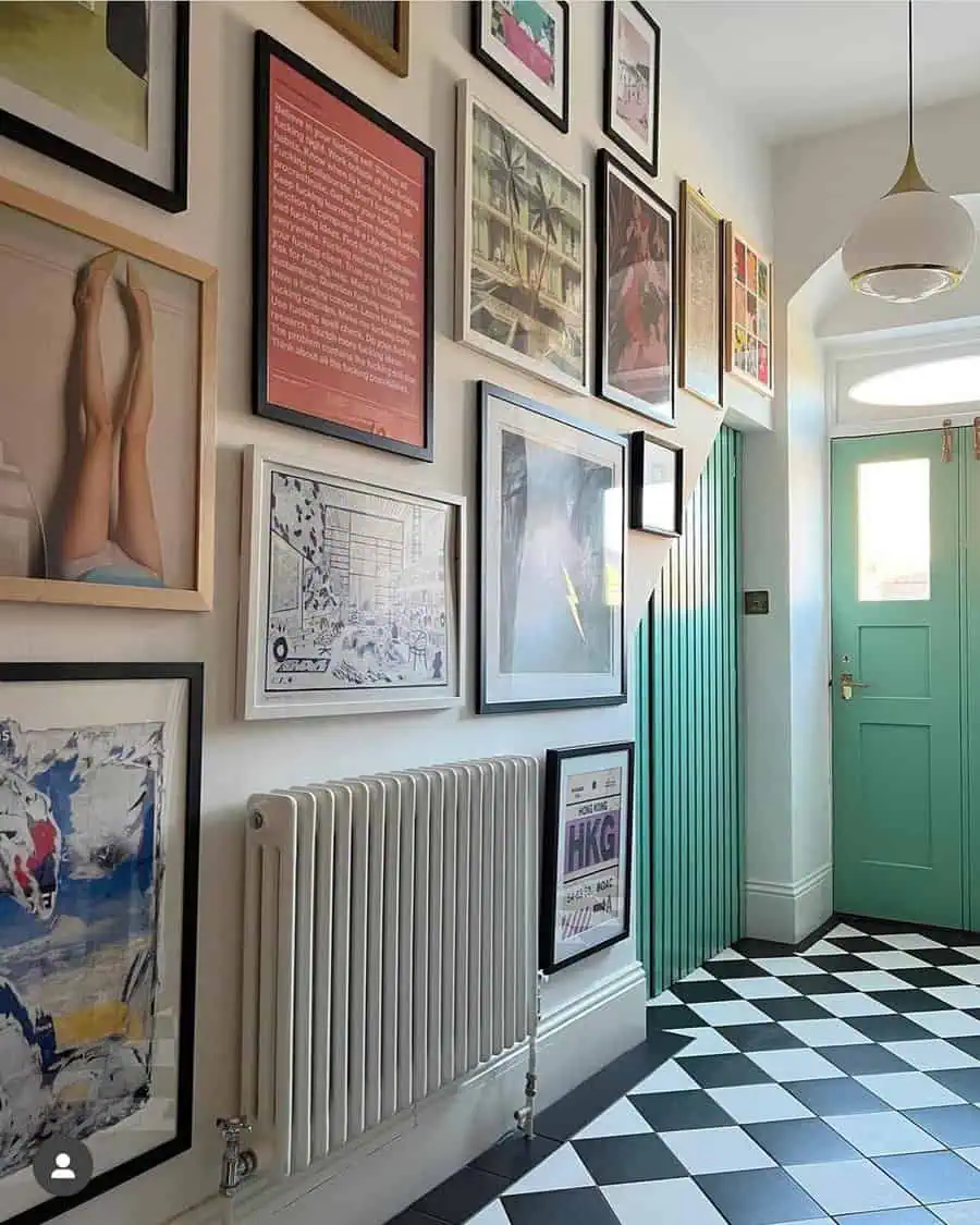 Creative gallery wall in a modern hallway with eclectic art and black-and-white checkered flooring.