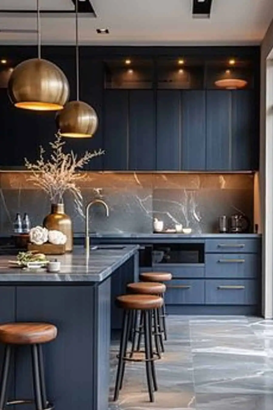 Modern kitchen with navy cabinets, gold accents, bar stools, and marble countertops