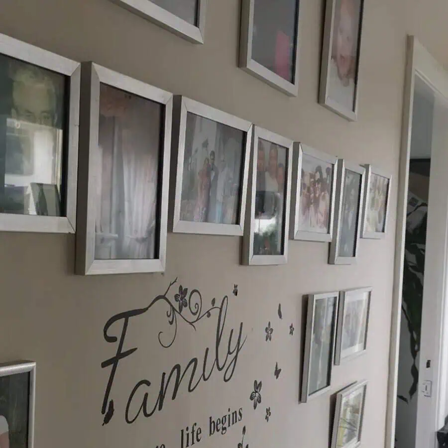 Family photo gallery wall with silver frames and a "Family" wall decal in hallway.