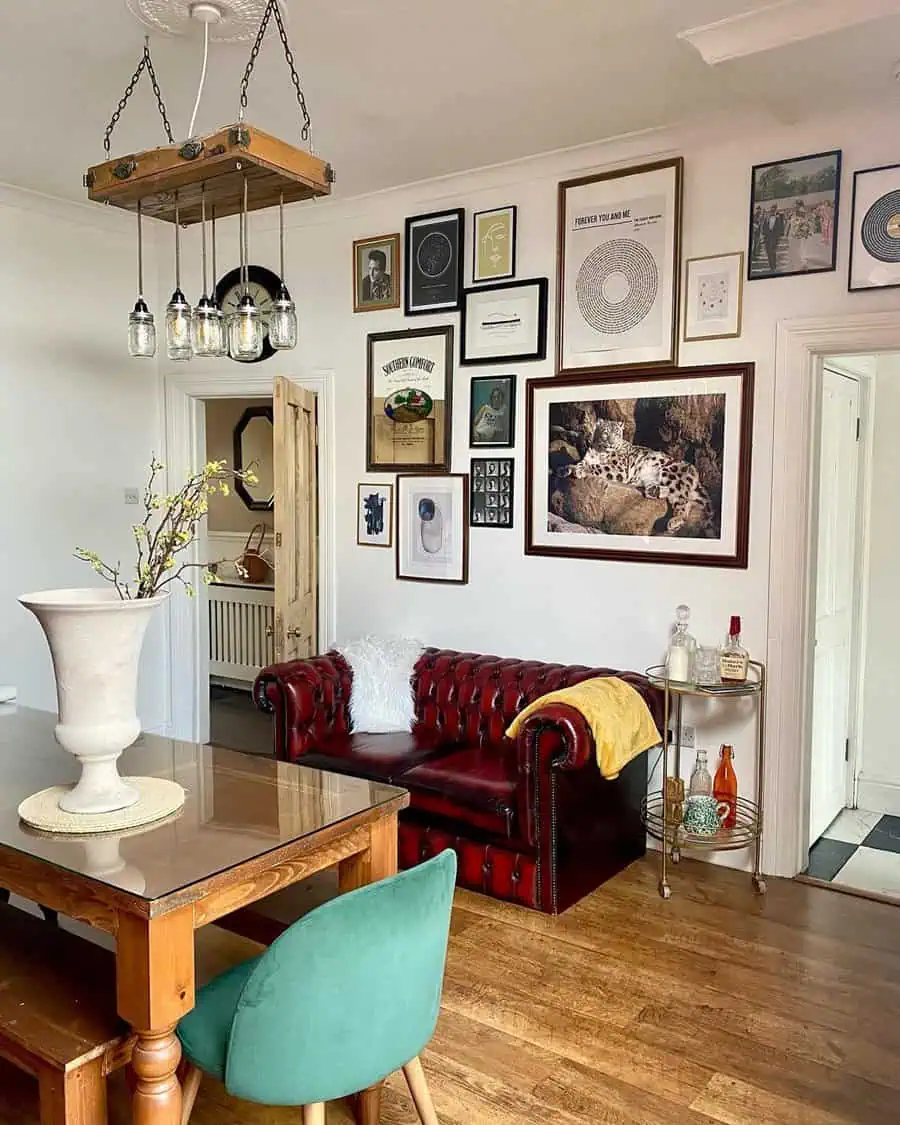 Eclectic gallery wall with vintage flair, leather Chesterfield sofa, and modern chandelier.