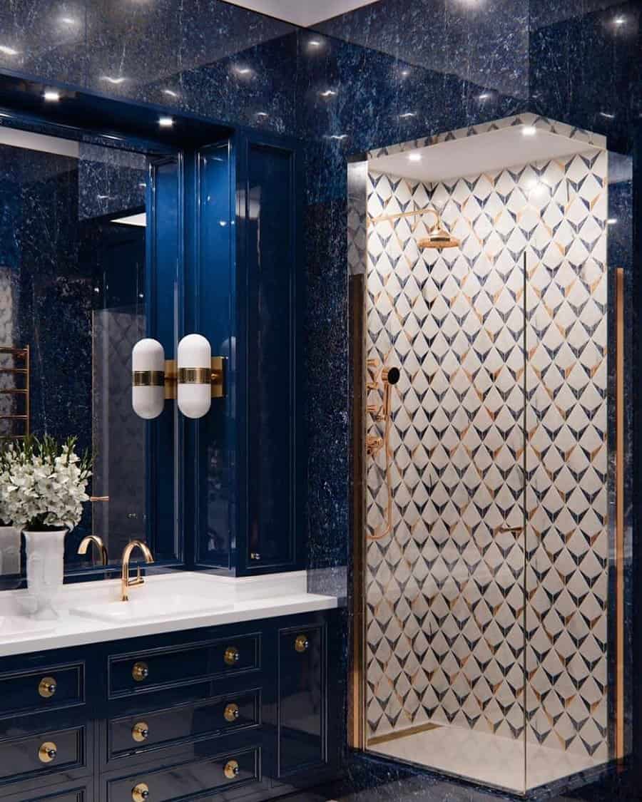 Luxurious bathroom with geometric tile shower, navy blue vanity, and gold fixtures.