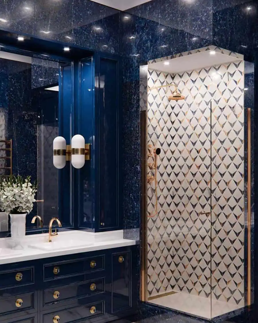 Luxurious bathroom with geometric tile shower, navy blue vanity, and gold fixtures.